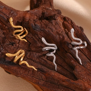 Miniature snake pattern ear clips in 18K gold and silver plating on dark wood background