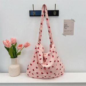 Vue lifestyle du sac cabas en velours côtelé rose à motif fraises sur mur blanc