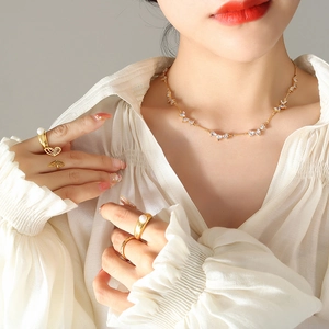Elegant gold butterfly zircon necklace and pearl ring set on model with chic blouse