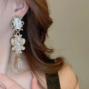 Detailed close-up of Baroque silver drop earrings with floral relief and crystals on model