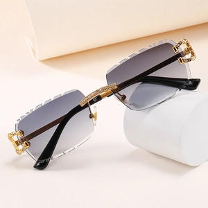 Detalle de gafas de sol rectangulares sin montura con patillas doradas y cristales engastados
