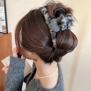 Détail d'une grande pince à cheveux cœur en acrylique floqué avec motif tacheté gris
