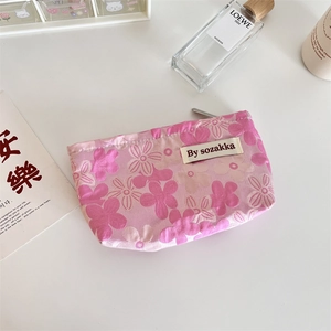 Detail of floral printed cotton makeup bag with metal zipper and brand label on desk