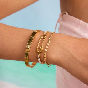 Détail de bracelets superposés en or avec zircons et jonc à motif de vis en cœur