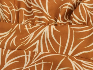 Detailed macro view of brown fabric with white palm leaf print and woven texture