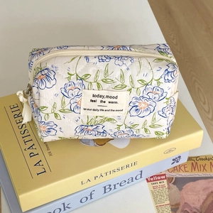 Close-up of quilted floral makeup bag with blue flower pattern on French style books