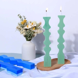 Detailed view of wavy green and blue geometric scented candles on a wooden tray
