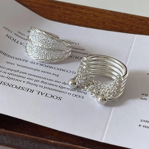 Detail of silver textured wide band ring and multi-layered ring with ball tassel detail