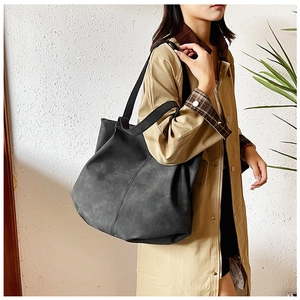Close-up of a large black matte suede tote bag worn on shoulder for daily commute