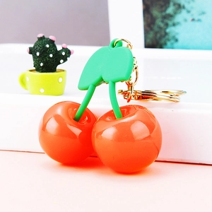 Close-up of glossy cherry keychain with green leaves and gold-tone metal ring hook