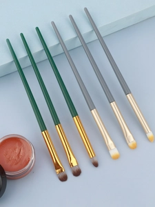Detailed view of professional eye makeup brushes with cream shadow on blue background