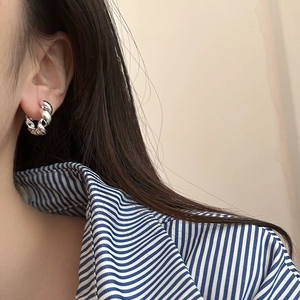 Detailed view of silver twisted rope hoop earring worn on an ear showing fine metal texture