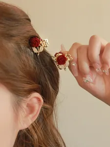 Detail of red velvet rose hair claw with sparkling rhinestones on golden alloy base