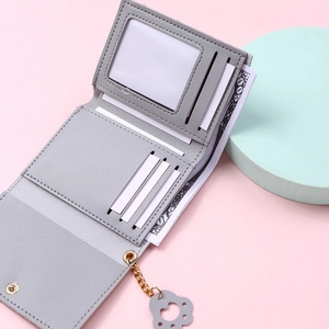 Detail of grey PU leather wallet featuring a golden cat paw charm and litchi texture