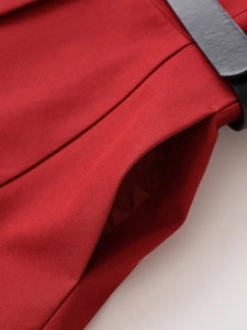 Close-up of deep red twill fabric featuring a side pocket and black belted waist detail