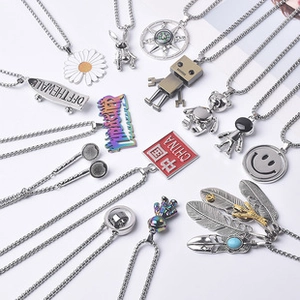 Flat lay of diverse Cuban chain necklaces with colorful astronaut and flower pendants