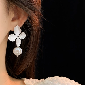 Close-up of a silver flower earring with a white freshwater pearl on a model