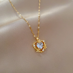 Close-up of heart-shaped gold necklace with zircon stones on champagne satin fabric
