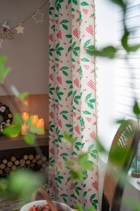 Close-up of Christmas curtain with holly leaves, berry patterns and tassel detail