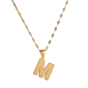 Detailed close-up of golden letter M pendant with dotted texture on a sleek chain
