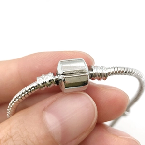 Macro shot of silver snake chain bracelet with square mechanical clasp closure