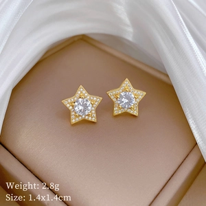 Macro view of gold star earrings with white zircon on champagne satin gift box