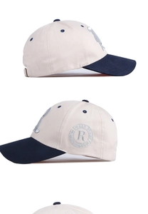 Detail view of contrast baseball cap showing cream fabric and navy brim with embroidery