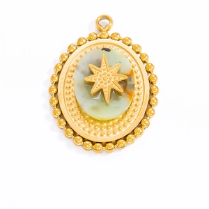 Detail of gold oval pendant with beaded edge, natural stone inlay, and star motif