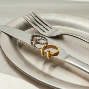 Polished gold and silver irregular open rings displayed on a minimalist metal knife