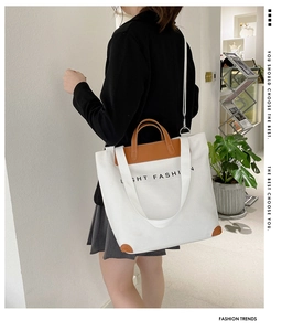 Detail showing the white canvas tote with brown leather trim and adjustable shoulder strap