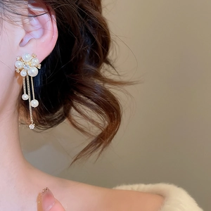 Detailed side view of elegant flower pearl tassel earrings worn by a female model