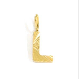 Macro shot of gold letter L pendant with detailed sunburst texture on stainless steel
