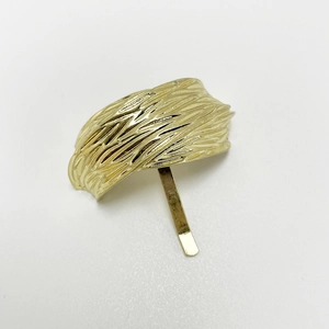 Detailed macro view of the gold-tone metallic hair clip showing intricate leaf texture