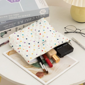 Quilted cotton makeup bag with colorful polka dots shown with various cosmetics