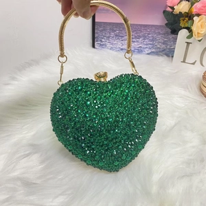 Close-up of heart-shaped evening bag with emerald green rhinestones and gold ring handle