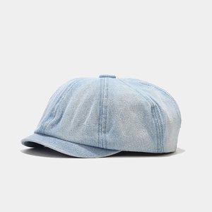 Detail view of light blue washed denim newsboy cap with soft twill texture and neat stitching
