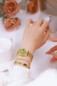 Detail of luxury gold women's watch with green dial and matching crystal bracelets