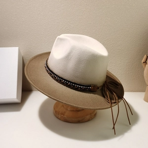 Detail of cream and brown jazz hat with rhinestone band and long tassels on wooden stand