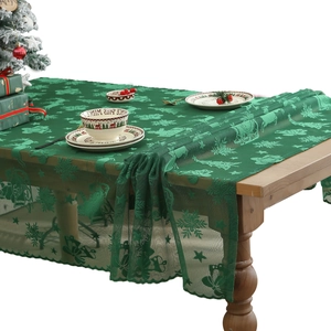 Green Christmas lace table runner with reindeer and snowflake patterns on a festive table