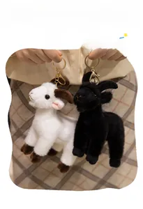 Close-up of cute black and white plush goat keychains with golden lobster clasps