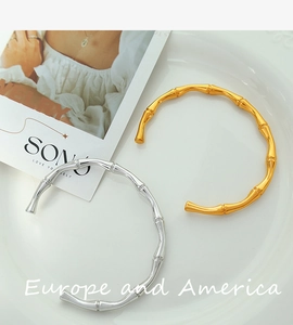 Detailed view of bamboo-shaped open bangles in gold and silver finish on a ceramic tray