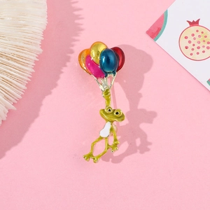 Détail d'un pin's grenouille en émail avec des ballons colorés et une finition polie