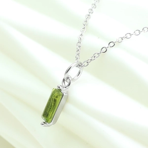 Close-up of a silver chain necklace featuring a rectangular green zircon pendant