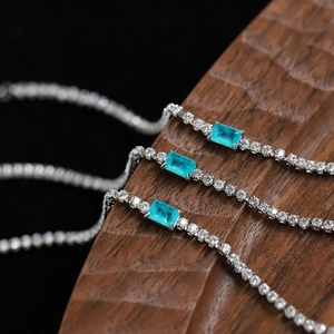 Elegant silver tennis bracelets with rectangular blue stones on a wooden background