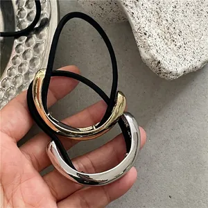 Minimalist gold and silver mirrored semicircular hair ties on a stone display