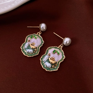 Close-up of vintage flower earrings with green enamel and white pearls on velvet