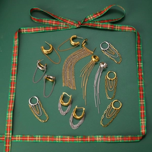 Mixed gold and silver long tassel earrings and ear cuffs on green festive background