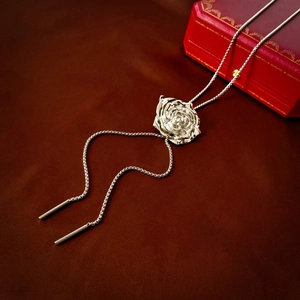 Detailed view of silver metal rose pendant on a brown silk background with a jewelry box