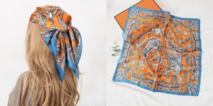 Detail of paisley print silk scarf in orange and blue with elegant hemmed edges
