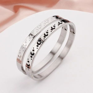 Pair of silver stainless steel star and moon engraved bangles with hinge closure